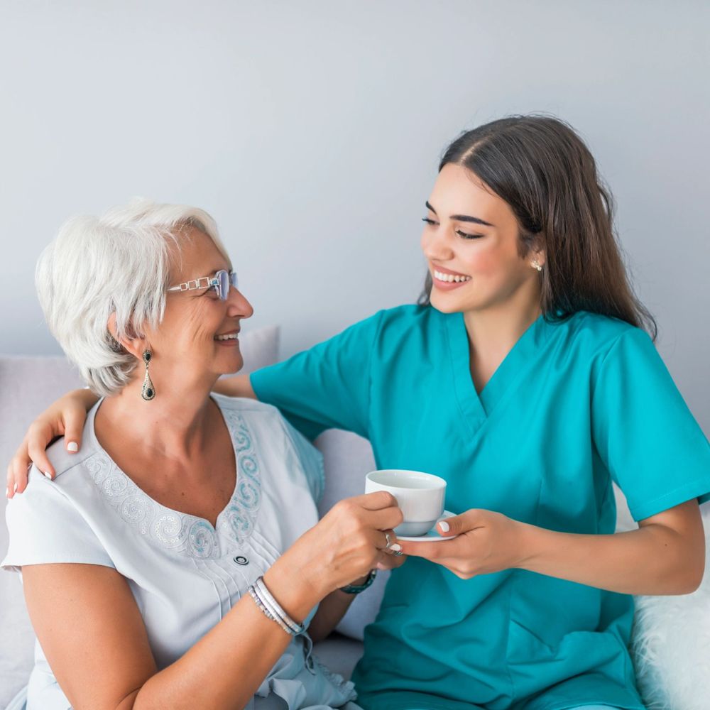 A caregiver and senior woman sharing tea and a smile