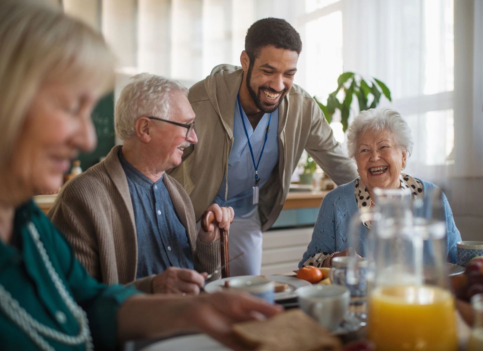 Seniors sharing a cheerful breakfast together with a caregiver